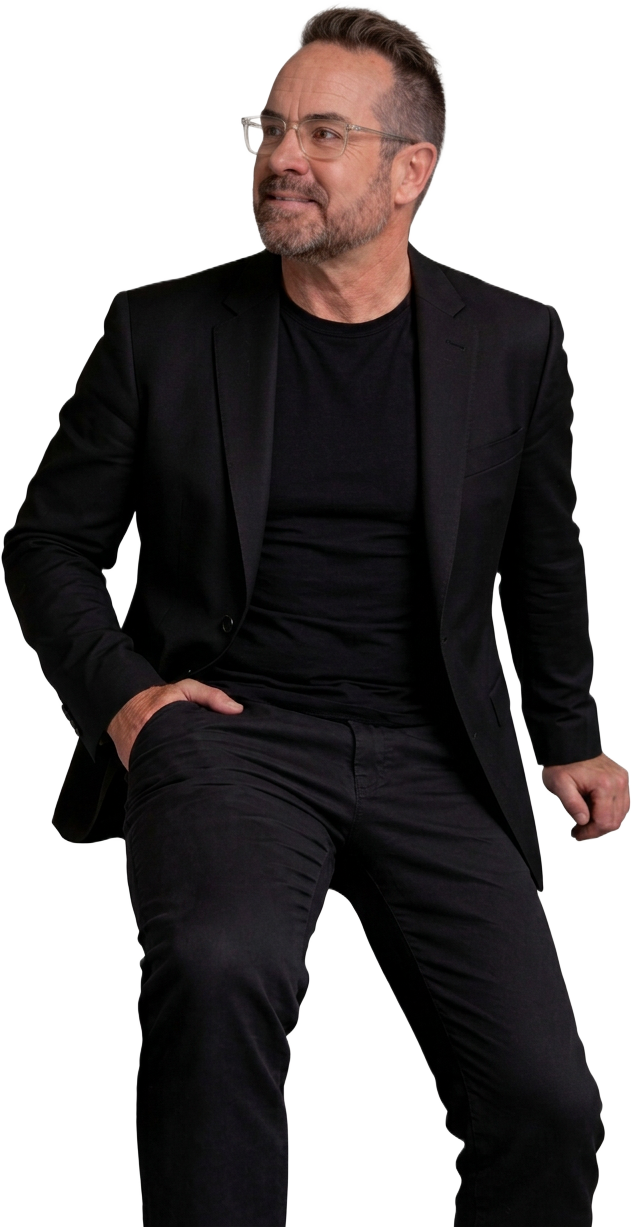 Michael McIntosh in a black suit, looking at his signature drumsticks